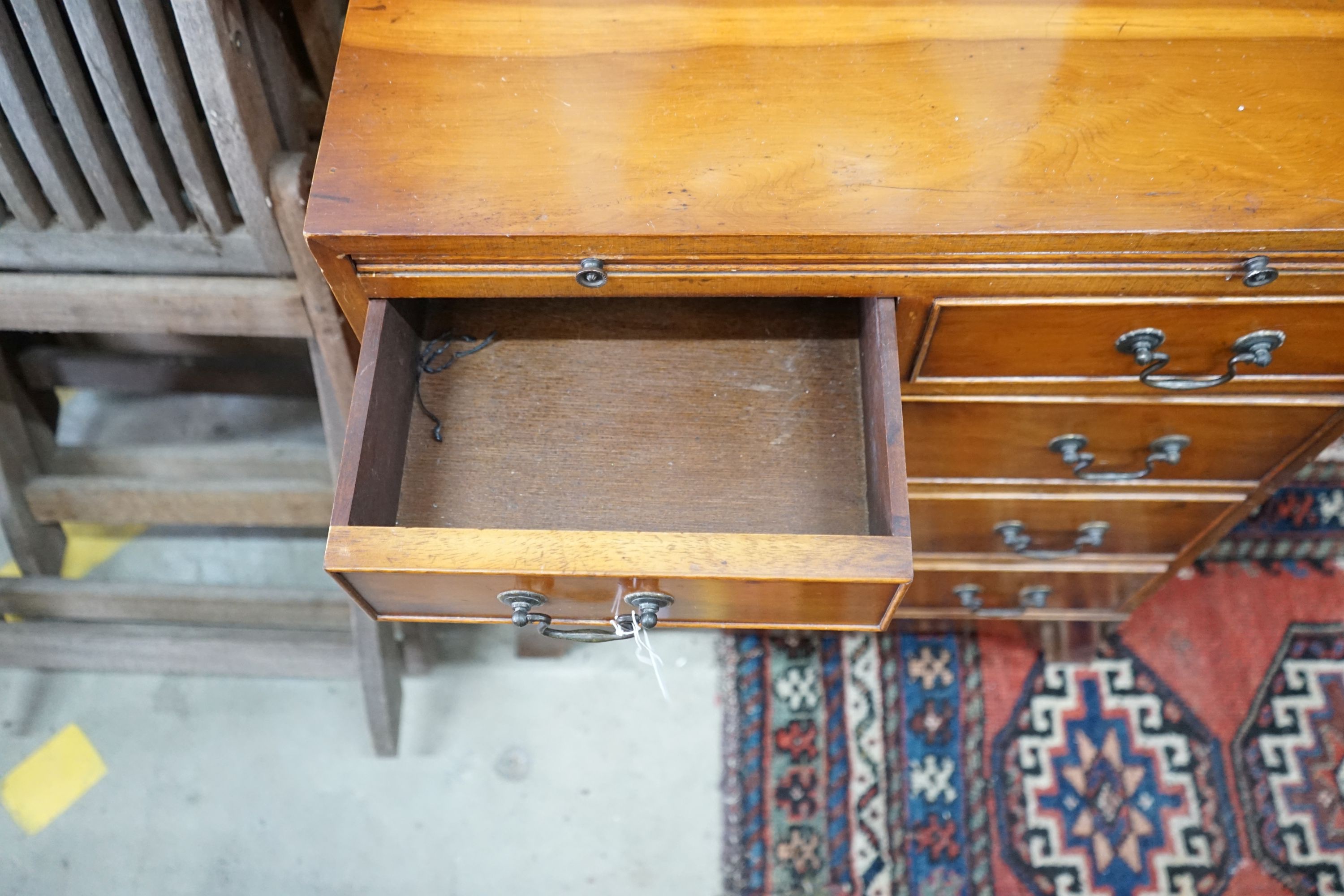 A small reproduction yew bachelor's chest of two short and three long drawers below brush slide, width 60cm, depth 40cm, height 74cm